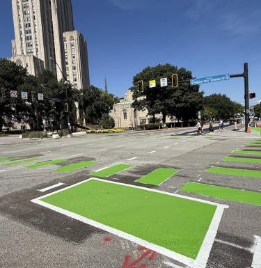 Pedestrian crosswalk painted bright green to indicate all-stop intersection at Forbes and Bigelow